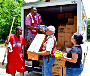Red Cross Volunteers Kraig Emmert and Lannie Steptoe (in truck) hand out a shovel, cleanup kits, snacks, and water to Humble, Texas, residents Rachelle and Willard Allen whose creek-side home was devastated by floodwaters. 