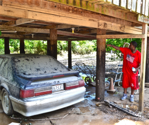 Willard Allen shows how high the water reached on the post supporting his carport. The car in the picture was completely submerged and destroyed by the flood waters.  